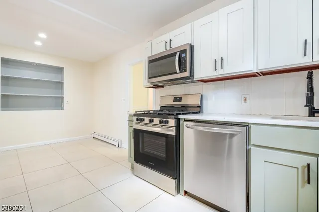 a kitchen with stainless steel appliances a stove a microwave and white cabinets