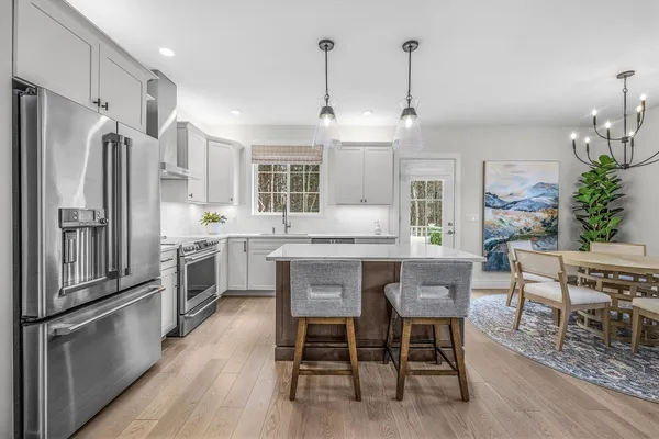 a kitchen with granite countertop a refrigerator a table and chairs in it