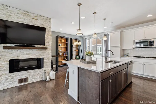 a kitchen with kitchen island granite countertop a stove top oven a sink dishwasher a dining table and chairs with wooden floor