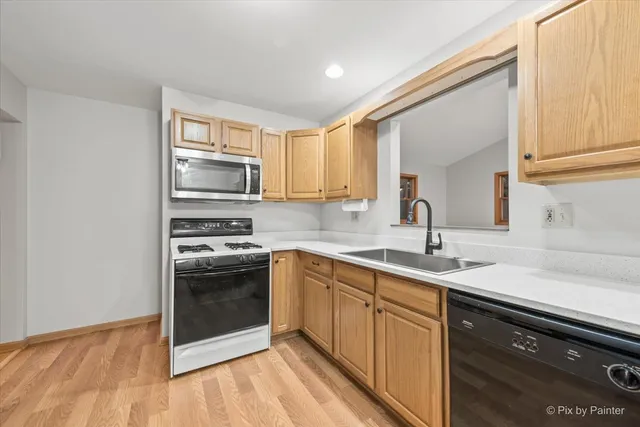 a kitchen with a sink cabinets stainless steel appliances and a window