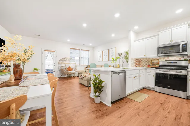 a kitchen with stainless steel appliances kitchen island granite countertop a stove top oven a sink a dining table and chairs