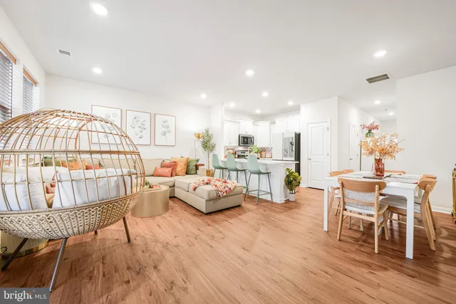 a living room with furniture a table and a dining table with wooden floor