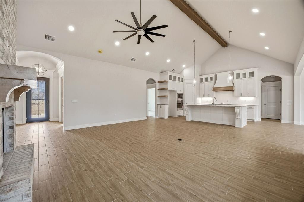 2017 Forest Bridge Azle, TX 76020 - Photo 11 of 30 Unfurnished living room featuring arched walkways, a ceiling fan, wood tiled floors, recessed lighting, and a fireplace with raised hearth