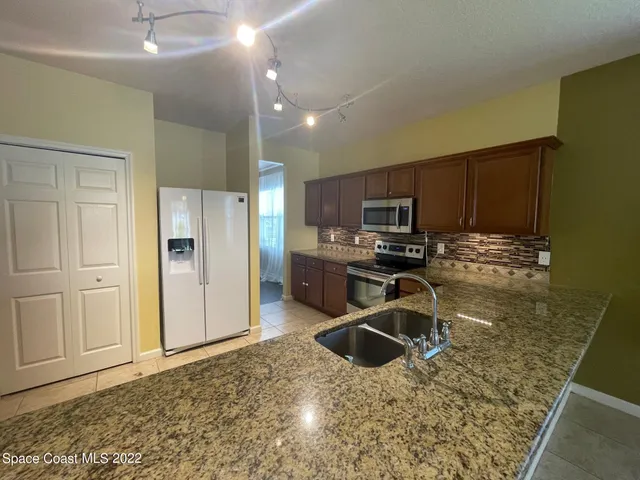 a kitchen with granite countertop a refrigerator and a sink