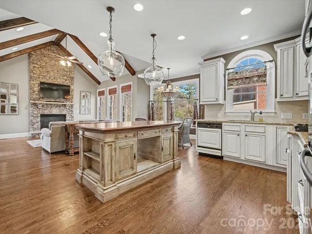 a open kitchen with stainless steel appliances granite countertop a stove a refrigerator a oven a dining table and chairs with wooden floor