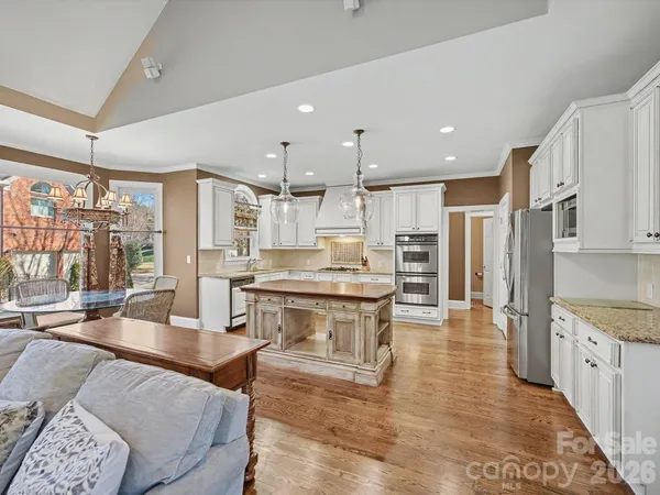 a large kitchen with a large counter top space a sink stainless steel appliances and cabinets