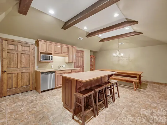 a kitchen with stainless steel appliances kitchen island granite countertop a refrigerator a stove a sink dishwasher and white cabinets with wooden floor