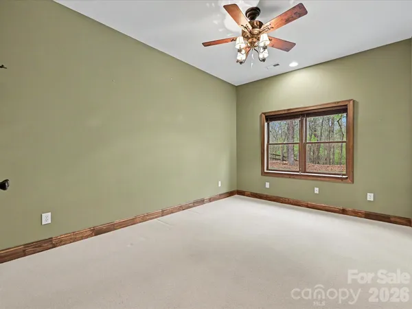 an empty room with windows and chandelier fan