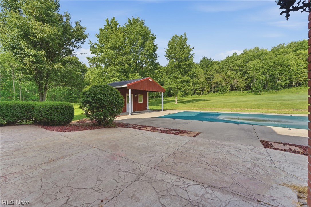 2184 Brenner Road Northeast Carrollton, OH 44615 - Photo 42 of 50 Stamped concrete patio with an expansive covered pool, a red utility shed, and mature perimeter landscaping