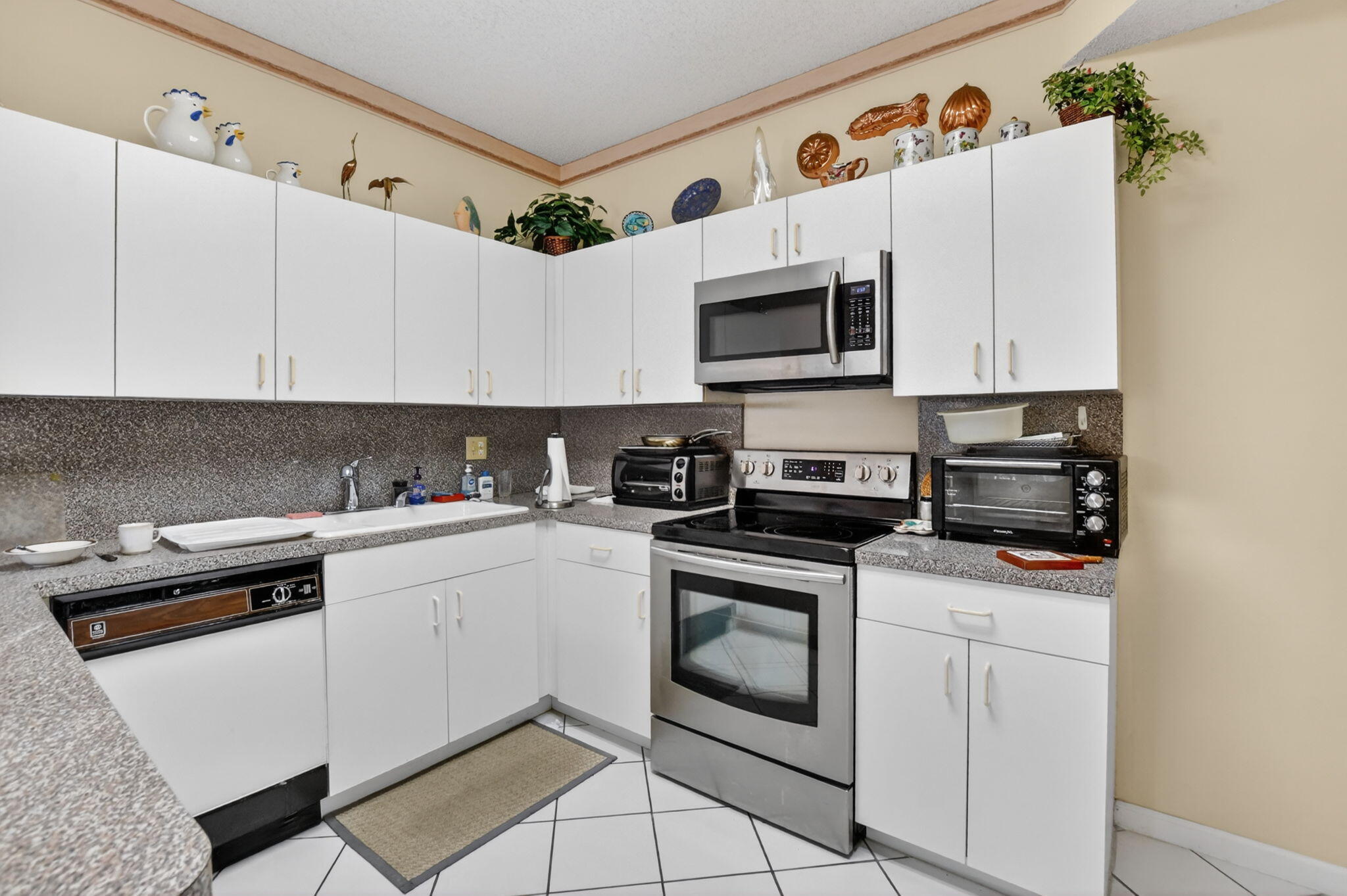6683 Montego Bay Boulevard, Unit C Boca Raton, FL 33433 - Photo 17 of 37 a white kitchen with stainless steel appliances granite countertop a stove a sink and white cabinets