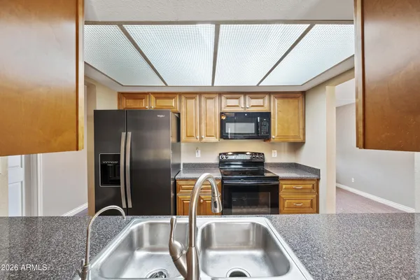 a kitchen with stainless steel appliances granite countertop a sink a stove and a refrigerator with wooden floor
