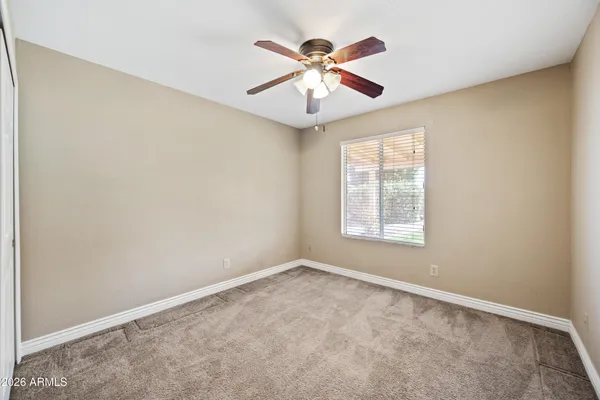 an empty room with ceiling fan and windows