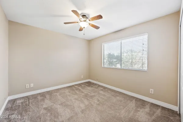 an empty room with windows and fan