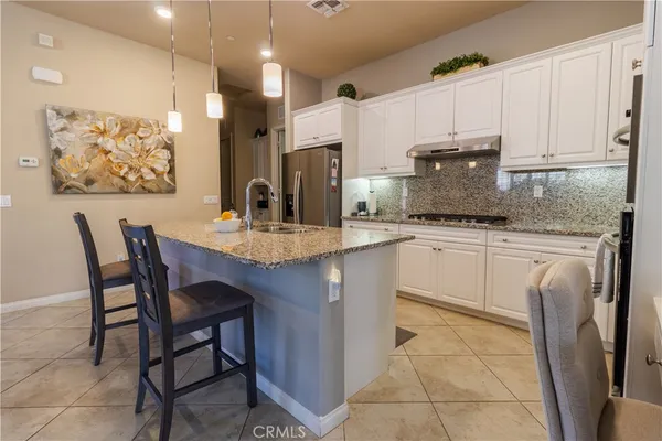 a kitchen with stainless steel appliances granite countertop a table chairs sink and cabinets