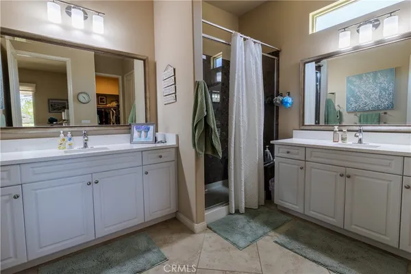 a spacious bathroom with double vanity a mirror and a shower