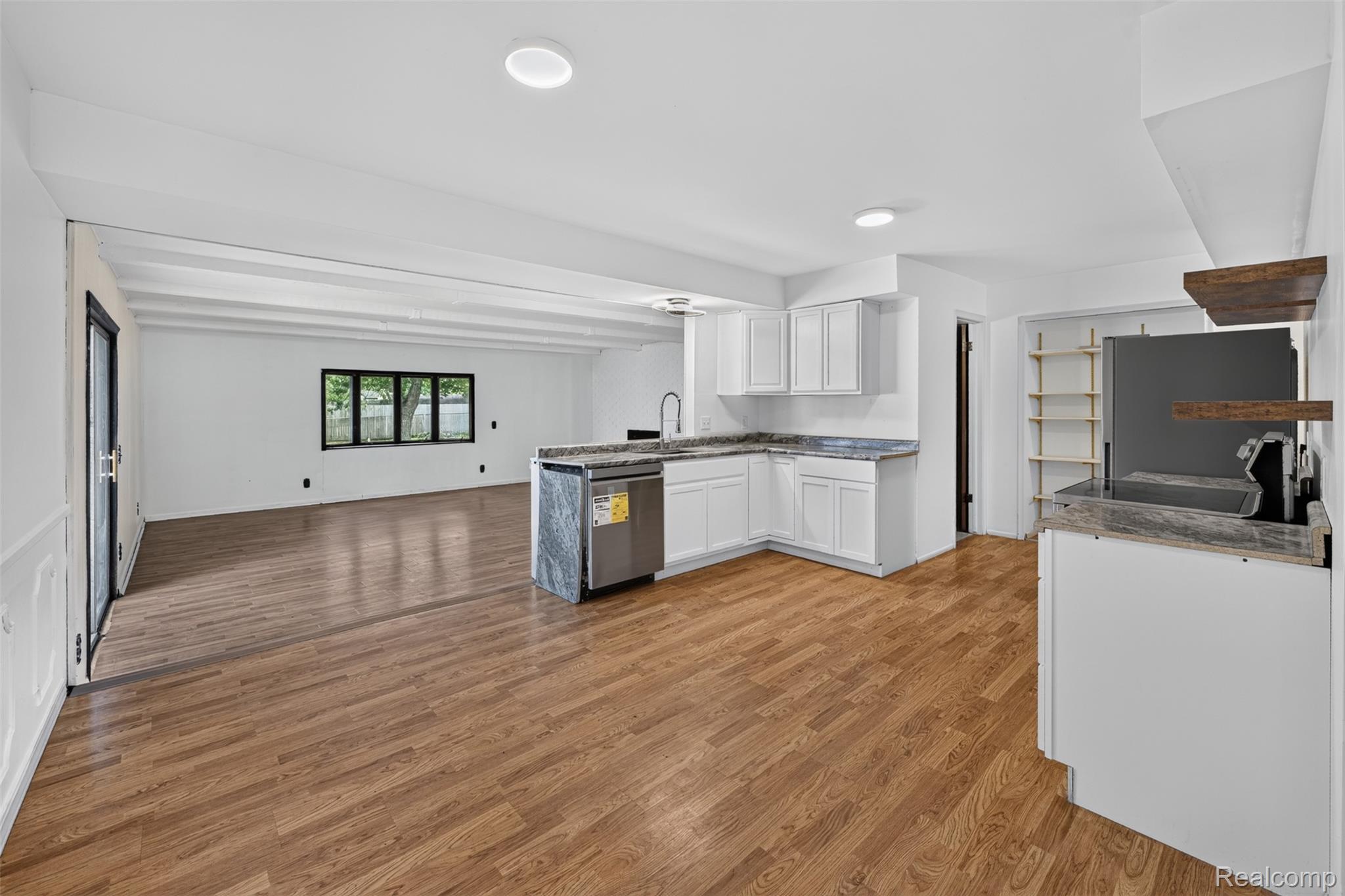 5457 Reid Road Swartz Creek, MI 48473 - Photo 12 of 51 Open-concept living space featuring wood-finish flooring, recessed lighting, a modern kitchen with white cabinetry, stainless steel appliances, and stone countertops