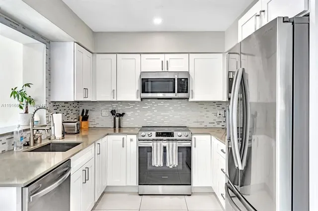 a kitchen with stainless steel appliances granite countertop a refrigerator a stove and a sink