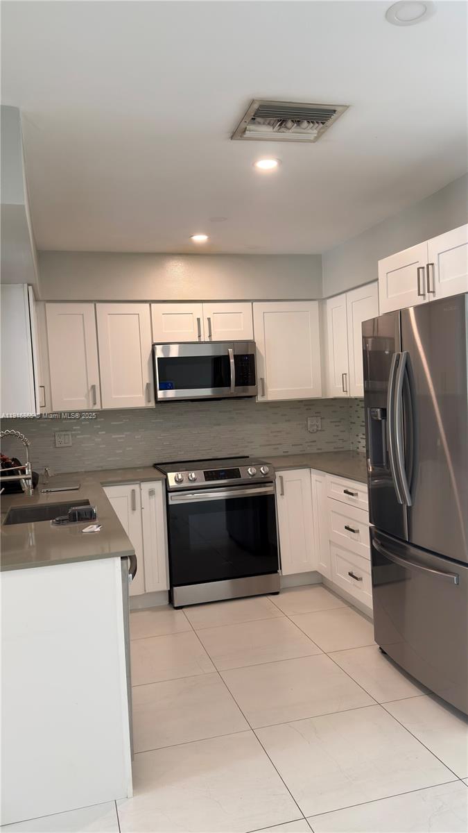 1577 Northeast 48th Court Oakland Park, FL 33334 - Photo 8 of 21 a kitchen with stainless steel appliances a stove a sink and a microwave