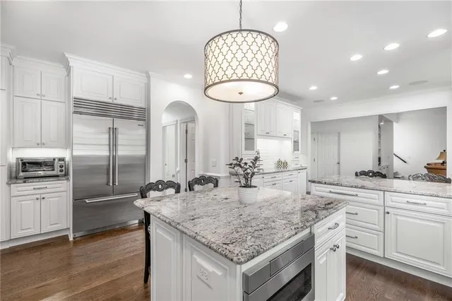 a open dining room with stainless steel appliances kitchen island granite countertop a dining table chairs and white cabinets