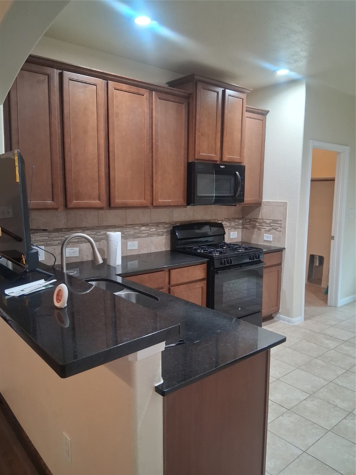 13610 Spectacled Bear Lane Crosby, TX 77532 - Photo 6 of 32 a kitchen with granite countertop a sink a stove and a microwave