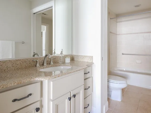 a bathroom with a granite countertop sink a toilet and a mirror
