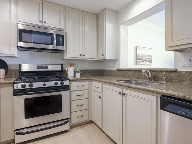 a kitchen with granite countertop white cabinets and stainless steel appliances