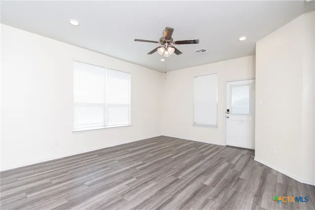 a view of an empty room with wooden floor and a window