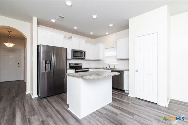 a kitchen with stainless steel appliances a refrigerator and a stove top oven
