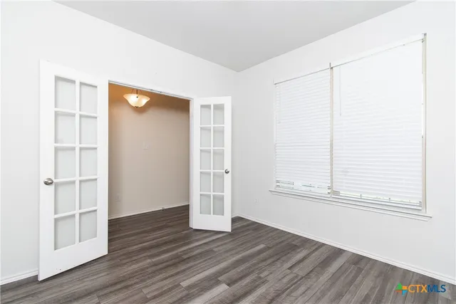 an empty room with wooden floor cabinet and windows