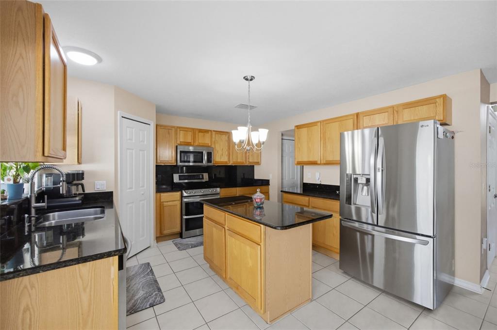 4517 Southeast 28th Street Ocala, FL 34480 - Photo 15 of 43 a kitchen with granite countertop a refrigerator oven a sink dishwasher and white cabinets with wooden floor