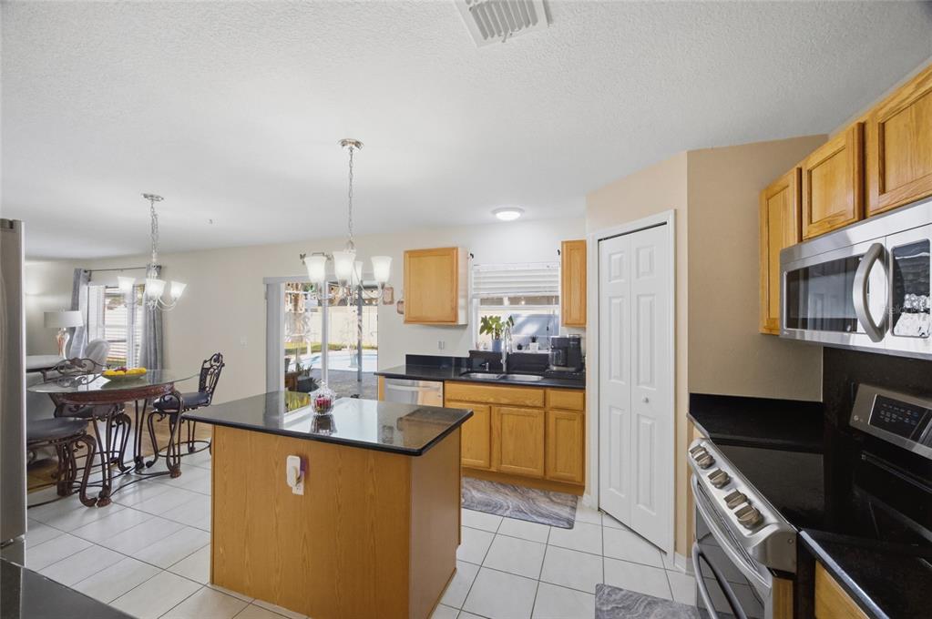 4517 Southeast 28th Street Ocala, FL 34480 - Photo 17 of 43 a kitchen with stainless steel appliances granite countertop a stove top oven a sink a dining table and chairs