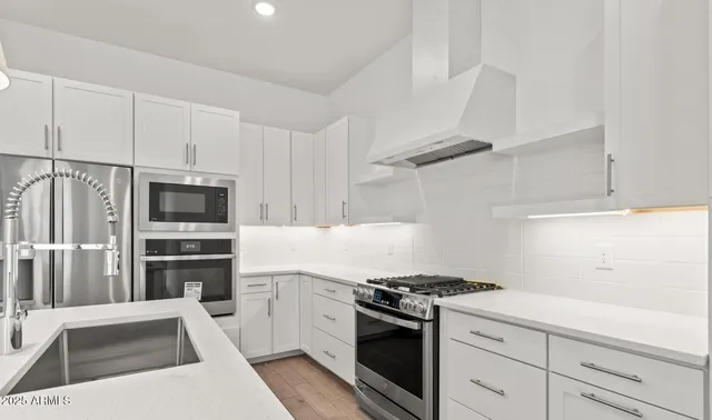 a kitchen with stainless steel appliances a sink a stove a refrigerator and cabinets