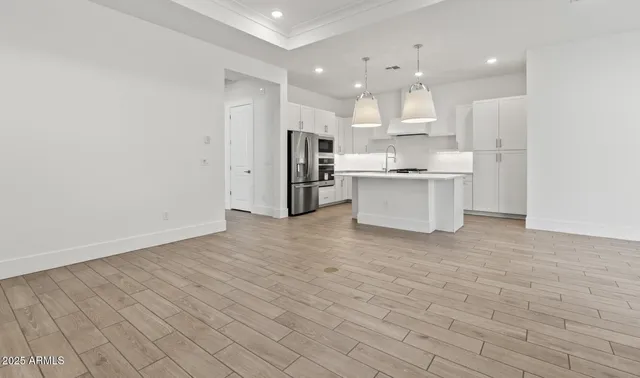 a large white kitchen with kitchen island a sink stainless steel appliances and cabinets