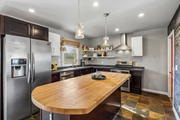 a kitchen with stainless steel appliances granite countertop a sink a stove a refrigerator and island