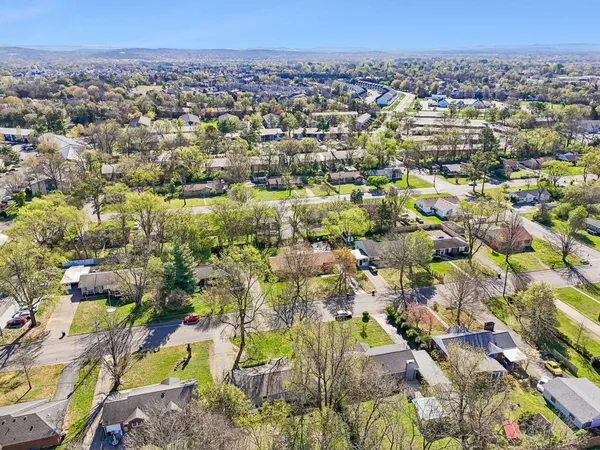 an aerial view of residential houses with outdoor space and trees