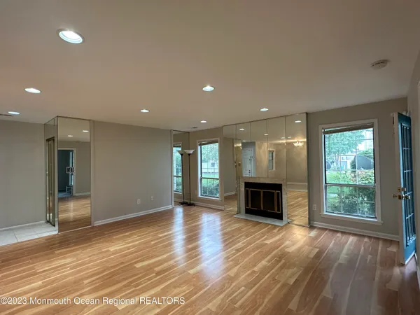 an empty room with wooden floor fireplace and windows