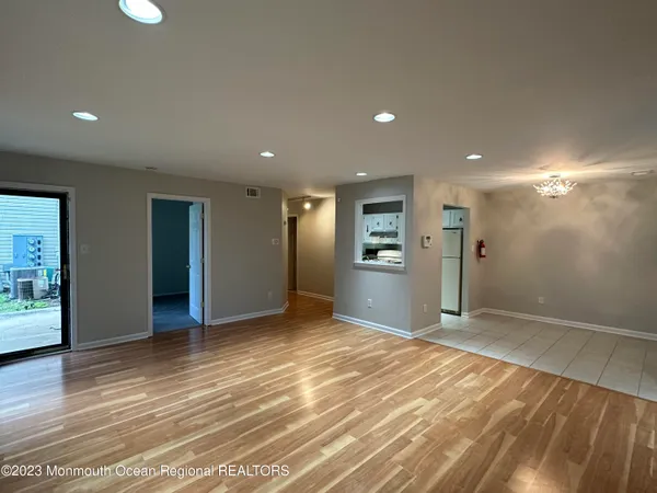 a view of an empty room with wooden floor and a bathroom