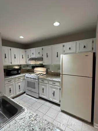 a kitchen with granite countertop a refrigerator sink stove and cabinets