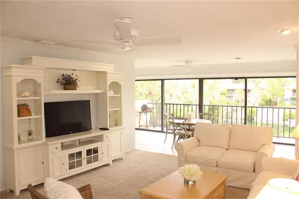 a living room with furniture a flat screen tv and a floor to ceiling window