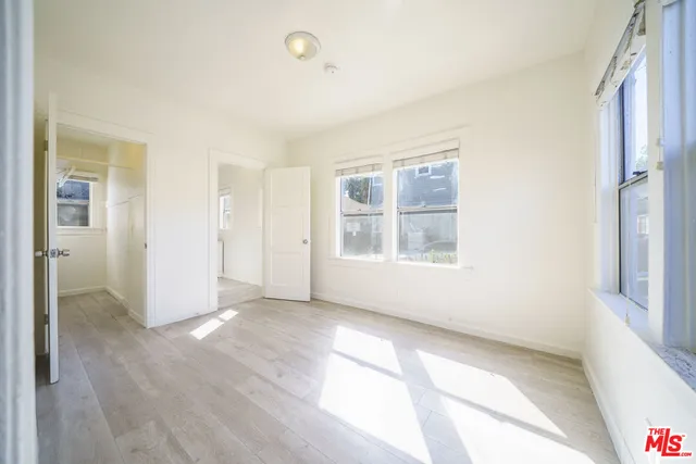 a view of an empty room with window and wooden floor