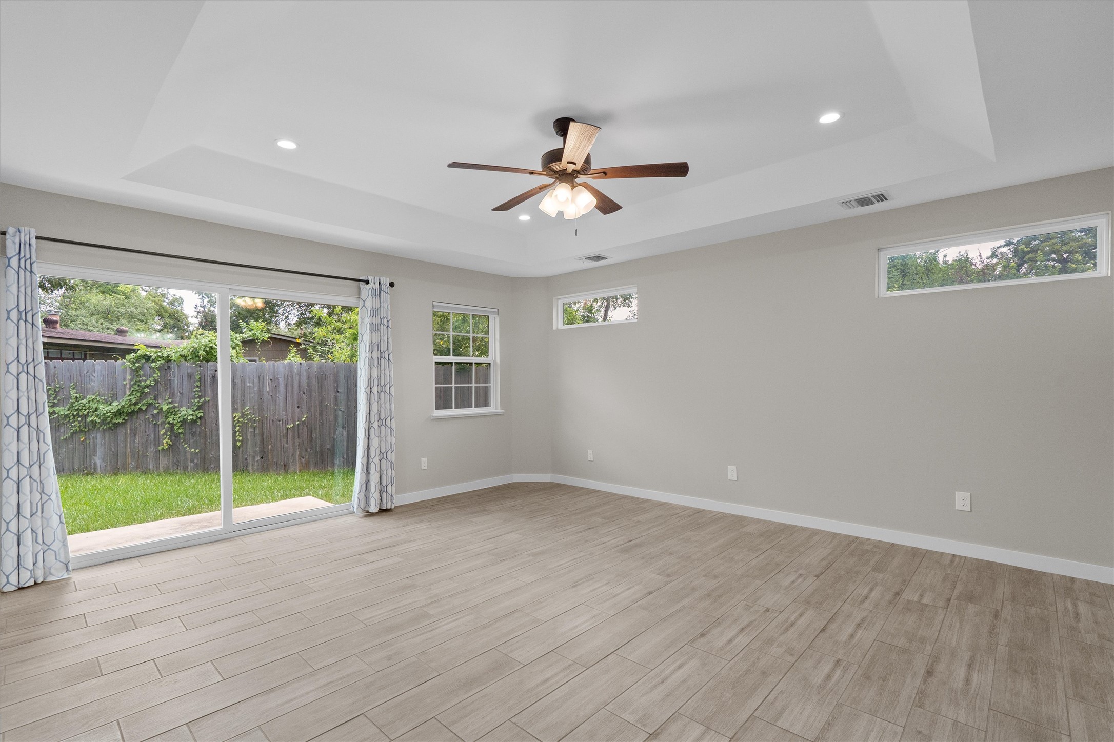 7707 Robalo Road Austin, TX 78757 - Photo 13 of 33 A spacious room offers direct access to a private yard, complemented by abundant natural illumination from transom windows and a multi-light ceiling fan.