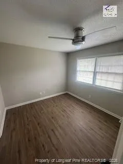 an empty room with wooden floor ceiling fan and windows