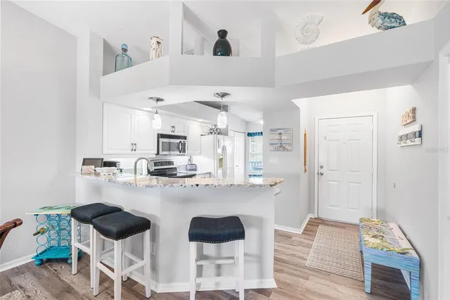 a kitchen with stainless steel appliances granite countertop a refrigerator a sink dishwasher a stove with white cabinets