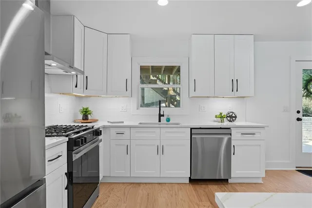 a kitchen with white cabinets and appliances