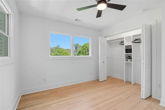 a view of empty room with wooden floor and ceiling fan
