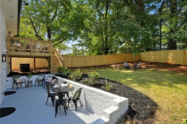 a view of a patio with table and chairs a barbeque with wooden fence and floor