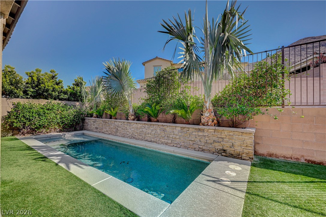 3943 Reyes Avenue Las Vegas, NV 89141 - Photo 56 of 95 A tranquil backyard oasis featuring a pristine in-ground pool, lush landscaping, and artificial turf.