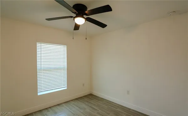 an empty room with a window and a fan