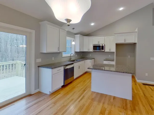 a kitchen with granite countertop a stove a sink and a refrigerator