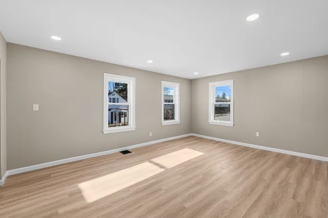 a view of an empty room with window and wooden floor